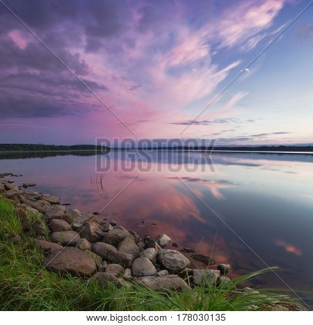 Pink sunset on the lake. Evening blue sky reflected in the water. Camping near the lake