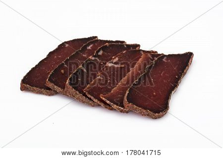 Dried beef basturma, chopped on white. Studio Photo