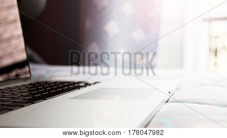 a laptop on the bed in the room in Paris writing fashion blog in Paris working at home or wathing movie on the bed. A silver laptop located on the bed near the window