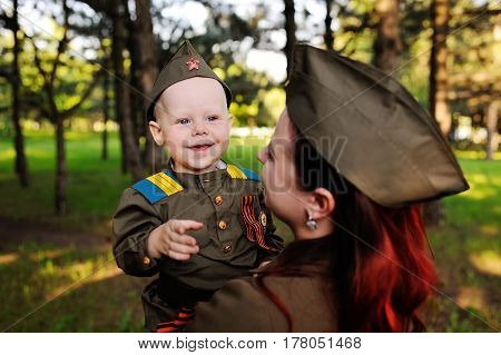 Mom and son in a military Soviet soldier uniform with St. George ribbons against the backdrop of nature. May 9, the day of victory, against fascism