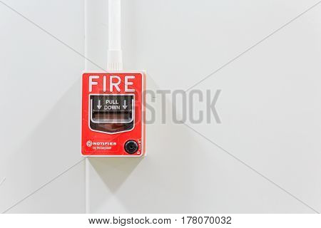 Fire alarm switch on white factory wall for warning and security system with copy space for your text.
