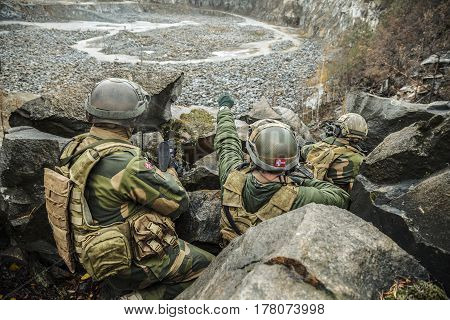 Patrol of norwegian Rapid reaction special forces FSK soldiers in field uniforms in ambush among the rocks guarding perimeter waiting enemy