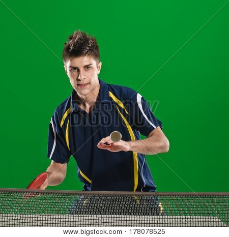 Young man in sportswear playing table tennis on green chromakey background