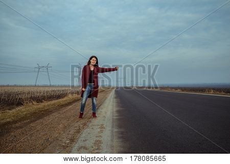 young woman travel with hitch-hiking couldy weather