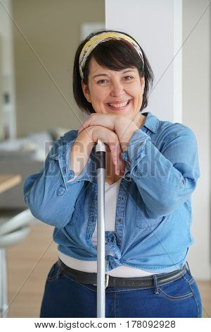 Cheerful overweigth woman having fun sweeping the floor