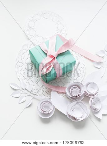 A Gift On A White Napkin And White Paper Flowers