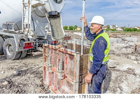 Zrenjanin Vojvodina Serbia - April 30 2015: Construction worker is holding leveling rod to help surveyor geodesist to measure position depth.