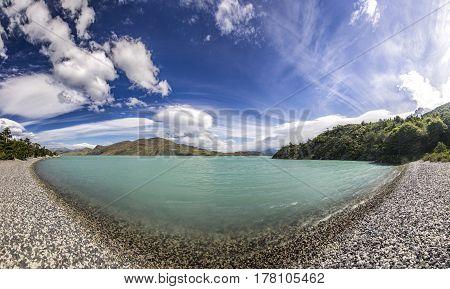 panorama of shore of blue lake and clouded sky in patagonia at daylight