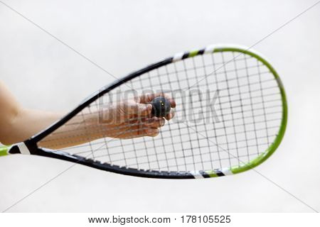 squash racket and ball in male hands. Racquetball equipment. Photo with selective focus. Player prepares to serve a squash ball. Closeup of hand serving ball