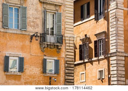 Old yellow facades of Italian houses with open wooden windows in the historical center of Rome