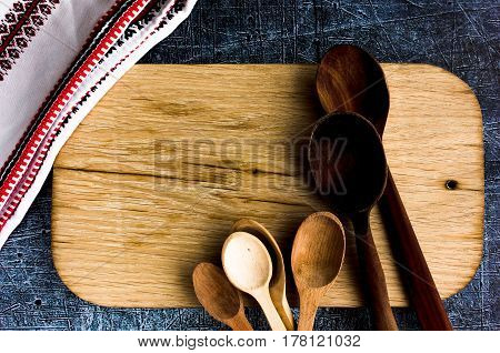 Rural kitchen board  With wooden spoons and old weave from above - grunge background with free text space. concrete background.  Different stuff. Top view. Copy space.