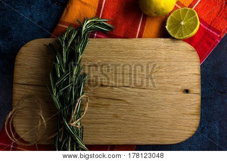 Rural kitchen board  With lemon , rosemary and old red cloth from above - grunge background with free text space. concrete background.  Different stuff. Top view.