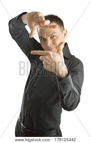 Focus on executive making frame with his hands on white background. Young happy man making frame with his hands looking at camera and smiling standing against isolated white background. He is dressed in a black shirt
