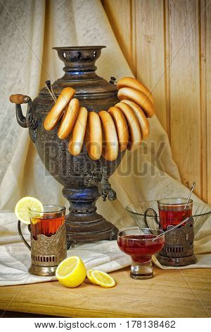 Russian samovar, tea with lemon in faceted glasses with cup holders and bublik. Tinted photo in vintage style.