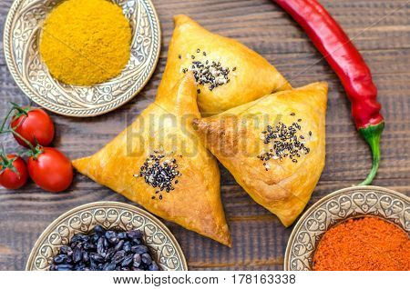 National Uzbek samsa dishes tomatoes red pepper and condiments on a brown wooden table