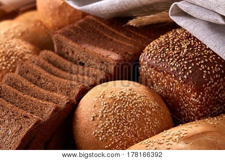 Assortement of Freshly baked traditional bread with ears of wheat and white cloth. Sliceas of the bread and rulls. Background of bread. Delicious food. Fresh baking. Tasty and appetizing.