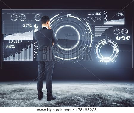 Back view of thoughtful businessman standing in front of digital business panel. Financial statistics concept. 3D Rendering