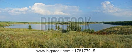 Panoramic view of the rural landscape. Blooming meadow and tortuous river in the late afternoon.