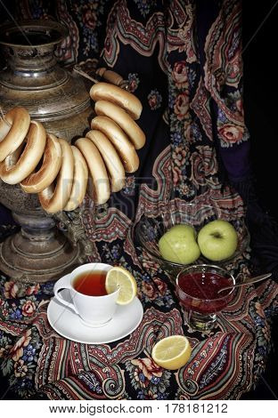 Russian samovar, tea cup with lemon and bublik. Tinted photo in vintage style on black background.