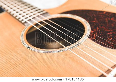 Closeup of steel strings and soundhole on an upscale acoustic guitar.