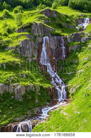 High in the mountains among the green meadows and rocks flows extremely beautiful rapid waterfall. Upper Svaneti Georgia Europe. Happy lifestyle. Beautiful universe.