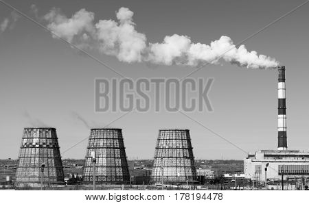 Thermal power station with smoking chimneys. View from afar. Horizontal black and white photo.
