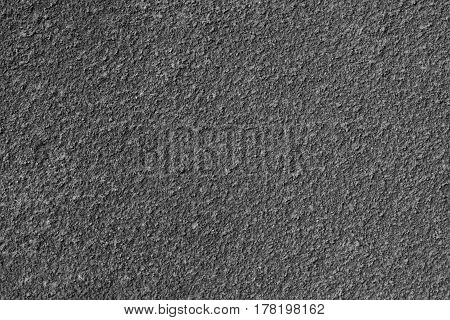 Texture of rough plaster. Horizontal background with a stucco exterior wall. Dark gray.