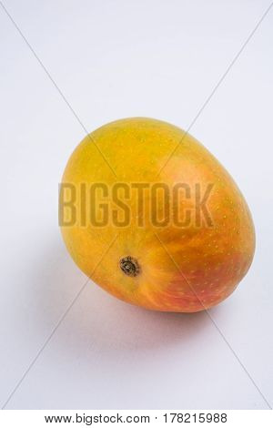 King of fruits; Alphonso yellow Mango fruit duo with stems and green leaf isolated over colourful background, a product of Konkan from Maharashtra - India