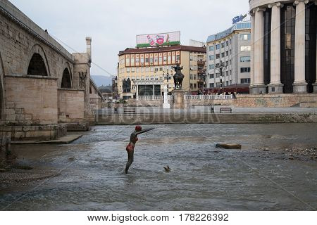 SKOPJE, MACEDONIA - March 20, 2017: Bronze statue of girl swimmer jumping in Vardar river at Skopje. Bronze statue of girl swimmer at Vardar river in Skopje, Macedonia.