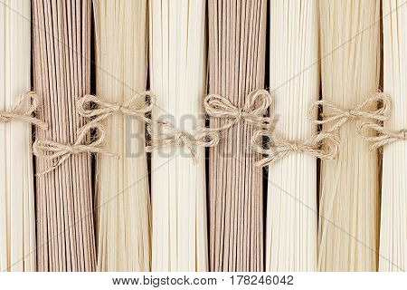 Raw japanese noodles different kind with decoretive bows top view. Border with copy space.
