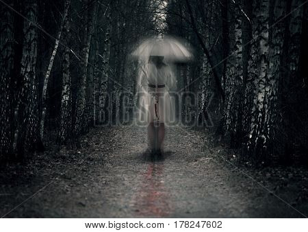 Scary woman ghost with knife stays in dark forest path