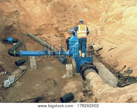 Main City Water Supply Pipeline. Technical Staff In Reflective Vest Underground