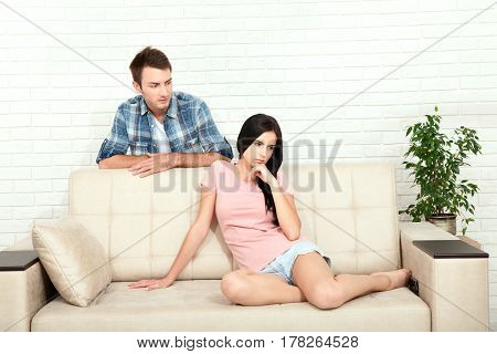 Insistent man trying to get sex and his worried girlfriend denying on couch at home. Angry woman rejecting a sex offer from her boyfriend.