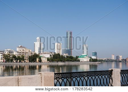 Skyline city center Yekaterinburg and Iset river in sunny summer morning. View from opposite bank of river.