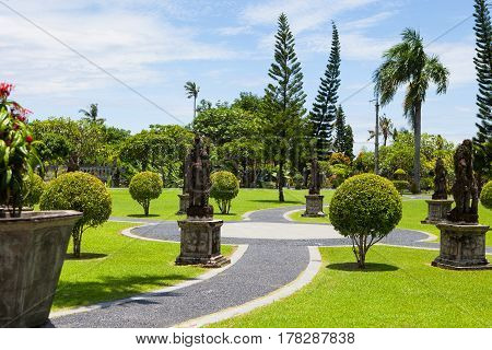 A stone path and shrubs of various shapes in the exotic Park in the tropics tirta gangga water Palace Taman Ujung