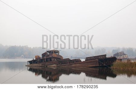 Old rusty sunken ship in water in a foggy day.