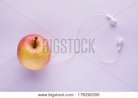 Apple With Earphones On Light Blue Background
