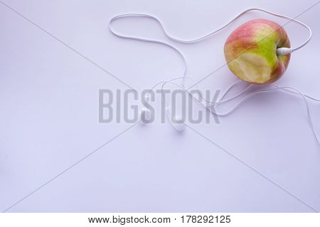 Apple With Earphones On Light Blue Background