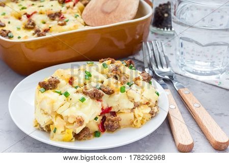 Egg casserole with potatoes sausage and pepper on white plate horizontal