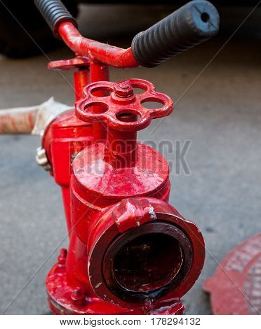 Red fire hydrant with connected hose. Close-up.