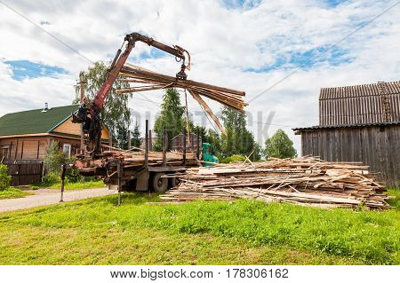 Novgorod region Russia - july 25 2016: Log hydraulic manipulator unloaded timber from the truck in summer day