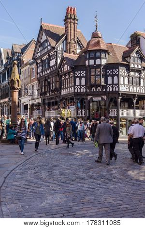 Chester England UK - March 25 2017: Shoppers and visitors on the corner of Eastgate and Bridge Street with the medieval stone cross in the historic city of Chester with its beautiful half timbered buildings