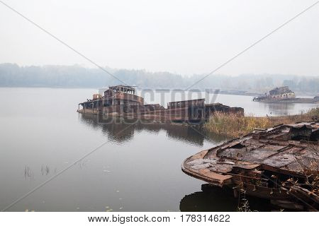 Old rusty sunken ships in water in a foggy day.