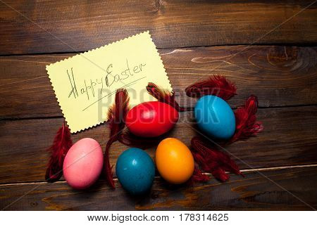 Red Feathers With Dyed, Whole Chicken Eggs For The Holiday With Leaf And The Inscription Happy Easte