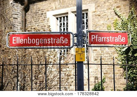 Nostalgic road signs of the Elbow-Street and Parish-Street in Mainz Gonsenheim in front of a church with a pointed fence.