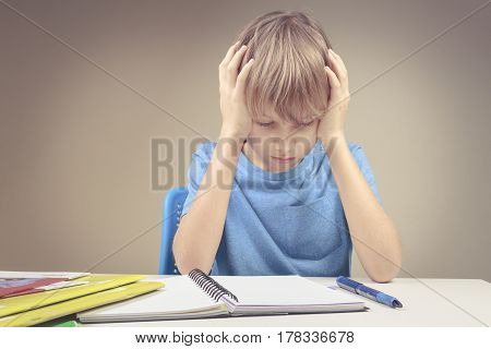 Concentrated child doing his homework at home. The boy sitting and looking in to books and notebooks. Education, school, learning difficulties concept