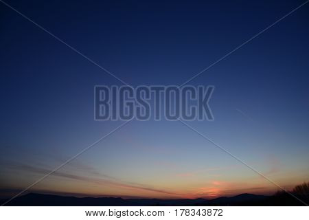 The clear sky is magenta and blue with alpenglow and few clouds. Free space for text. Abstract blue orange sky. Dramatic blue sky at the sunset background.