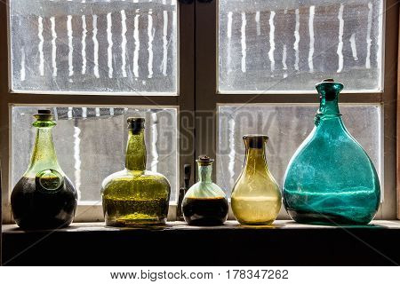 A Colorful Past;
From another era in a fort along the California coast. Bottles are of different sizes and colors. Framed scratched and worn windows add character. Blue, yellow, green glass bottles.