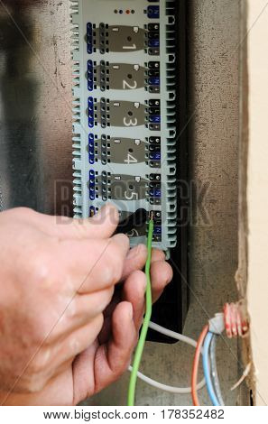 Man's hands inserts wires in a switch for thermostats and servo drives valves in a home heating system.