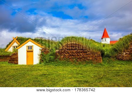 Museum-estate Glaumbaer, Iceland. The concept of the historical and cultural tourism. Church bell tower with a peaked red roof in old village of  houses covered with turf